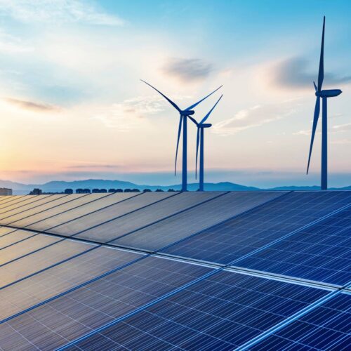 solar panels and wind turbines at sunset